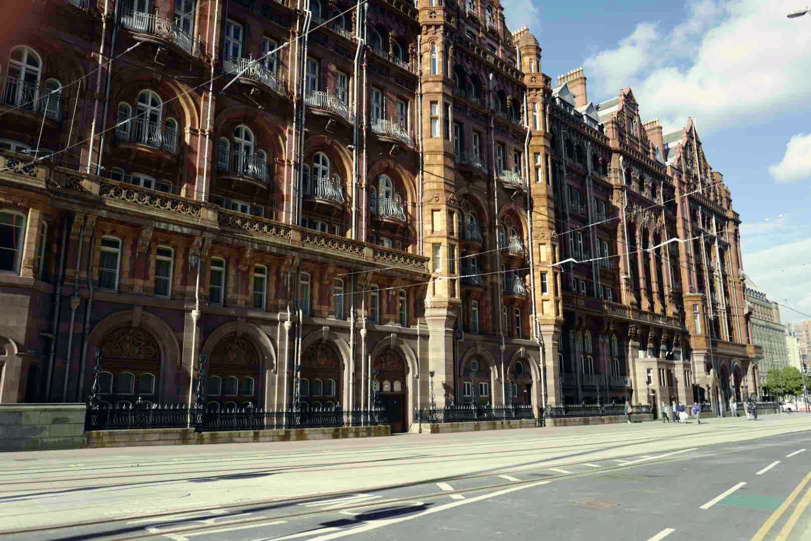 The ornate terracotta facade of a grand Victorian building along a Manchester street.